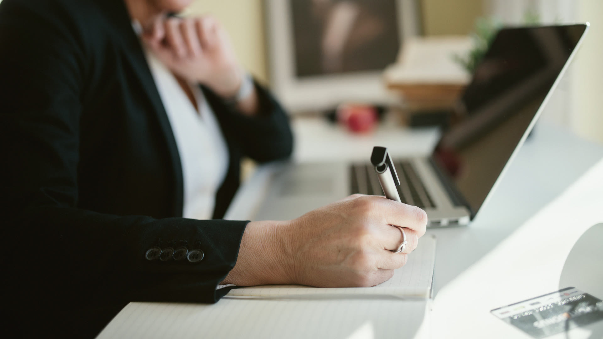 Preparing a bank application at a desk: handwritten notes beside a laptop and a bank card
