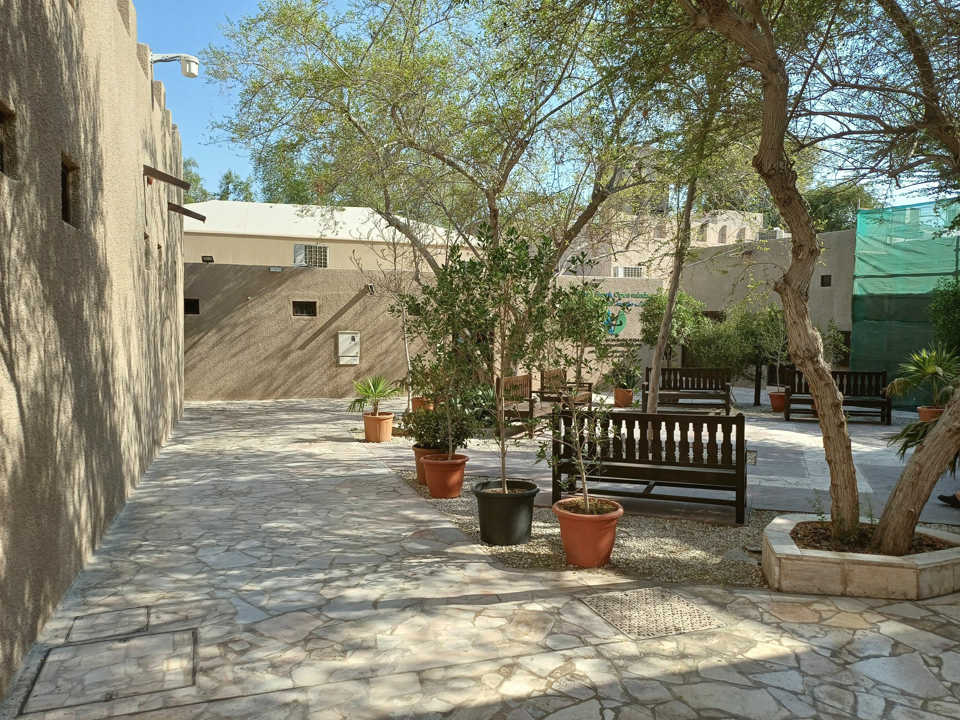 A shaded courtyard in the Al Fahidi district of Dubai, with benches and potted trees