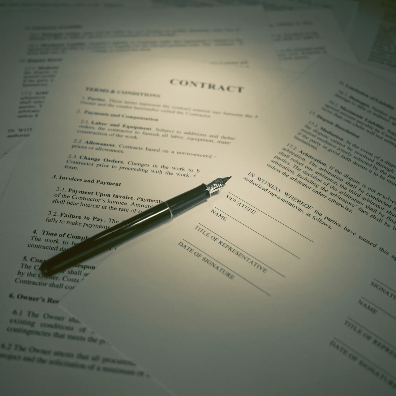 A contract laid out on a desk with a fountain pen resting on the signature line